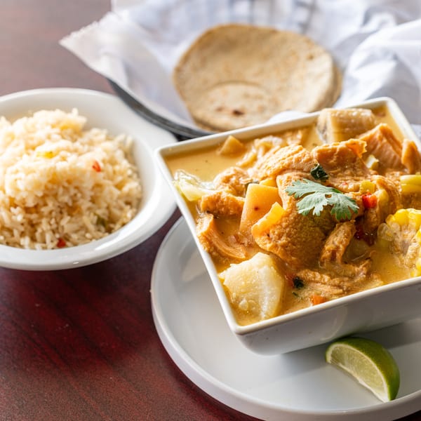 Hearty tripe soup with corn, potatoes, and cilantro, served with rice and tortillas.